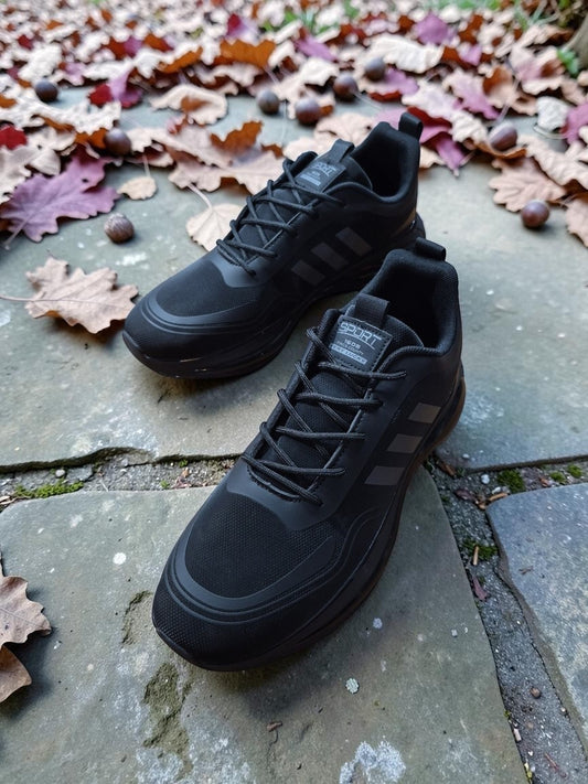 PUNK men's black and grey athletic sneakers with mesh and synthetic overlays on a stone path with autumn leaves